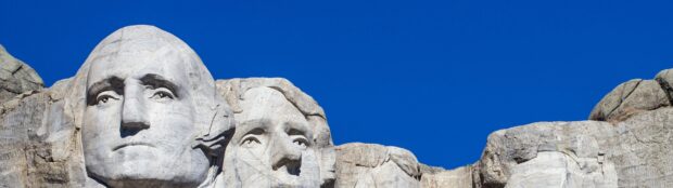 A detailed close up view of the carved faces on Mount Rushmore under a clear blue sky, 4K Desktop Wallpaper