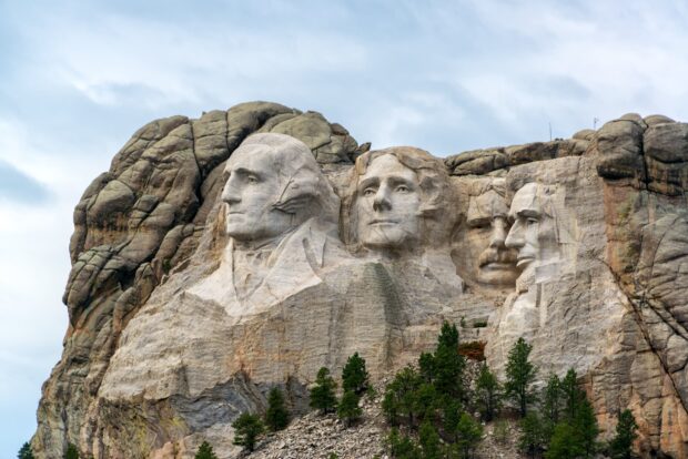 The Mount Rushmore sculpture shows four presidents carved into a mountain with a forest below, HD Desktop Wallpaper