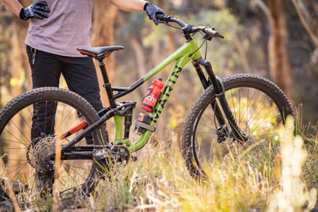 A person stands beside a green Marin bike on a forest trail, HD Desktop Wallpaper