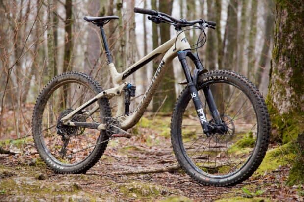 A dirty mountain bike stands on a forest trail covered with leaves and moss, HD Desktop Wallpaper