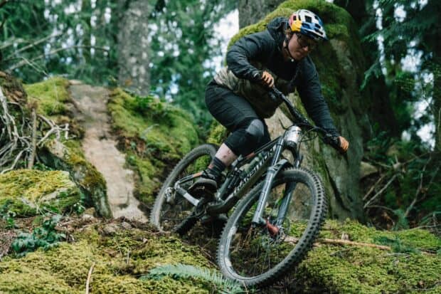 A cyclist is navigating a rugged forest trail on a Transition bike with intense focus, 2K Desktop Wallpaper