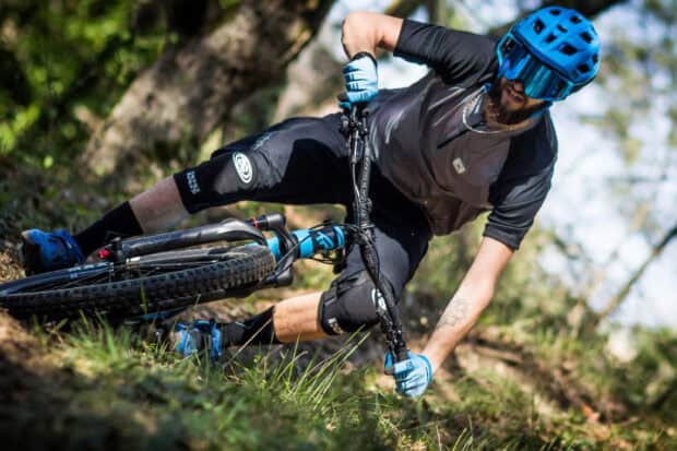 A mountain biker wearing protective gear is riding a sharp turn on a dirt trail, 2K Desktop Wallpaper