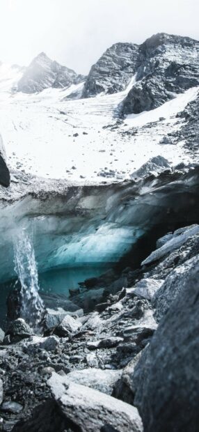 A mountain glacier with icy water flowing through rocky terrain, 2K Mobile Wallpaper