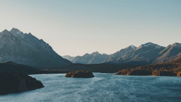 A serene view of Nahuel Huapi surrounded by mountains and calm waters at sunset, HD Desktop Wallpaper