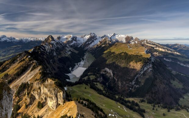 This image shows a mountain range in Liechtenstein with snow capped peaks and green valleys, 2K Desktop Wallpaper