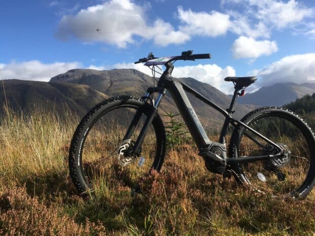 A Cube Bikes mountain bike is resting on grass with mountains in the background, HD Desktop Wallpaper