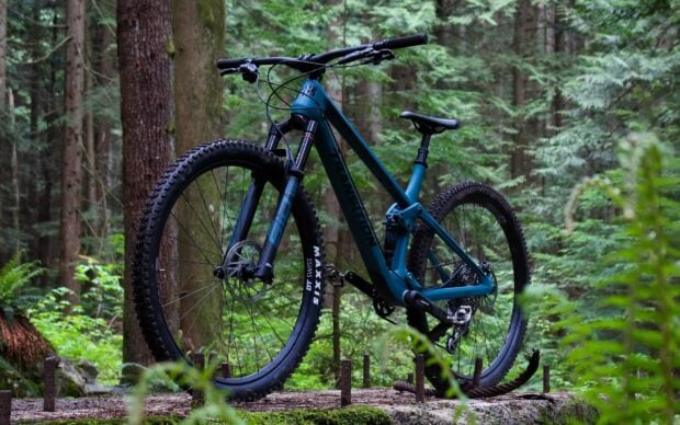 A blue Transition bike is parked on a forest trail surrounded by trees and greenery, HD Desktop Wallpaper