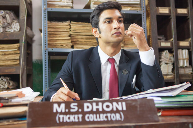 A man named Ms Dhoni is seated at a desk surrounded by files looking serious, HD Desktop Wallpaper