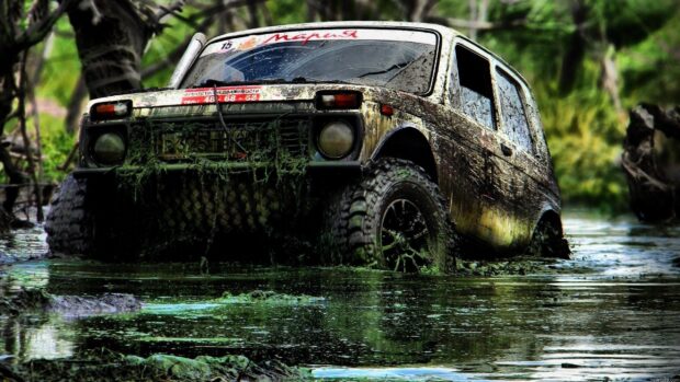 A muddy off road vehicle is driving through a swampy water area in the forest, 2K Desktop Wallpaper