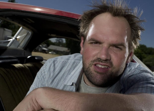 A close up of the main character from My Name Is Earl TV series sitting by the car, 2K Desktop Wallpaper