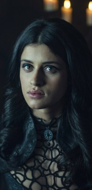 The image shows a mysterious woman from The Witcher TV series wearing a detailed black outfit and pendant, 2K Mobile Wallpaper