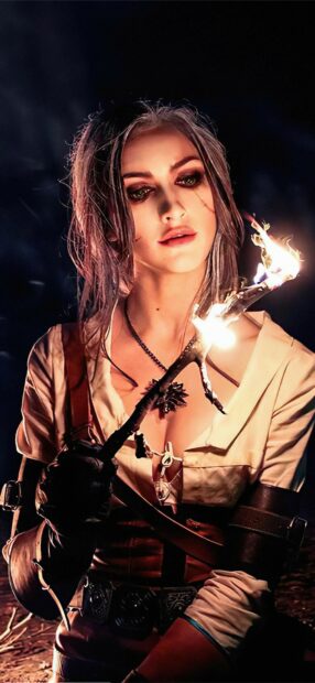 A mystic Witcher character holding a glowing torch in a dark environment, HD Mobile Wallpaper
