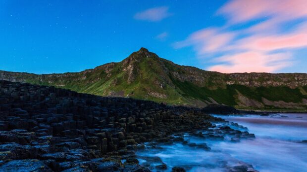 The Giants Causeway shows unique basalt columns under a colorful sky at dusk by the sea, 4K Desktop Wallpaper