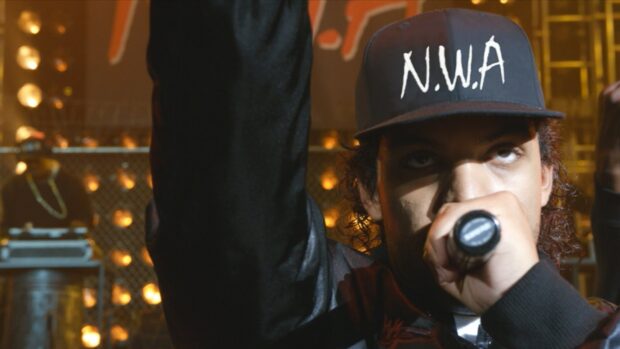 A rapper wearing an N.W.A cap is performing with a microphone on stage, HD Desktop Wallpaper