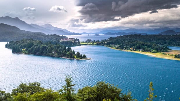 A scenic view of Nahuel Huapi with blue waters and green forests under a cloudy sky, 4K Desktop Wallpaper