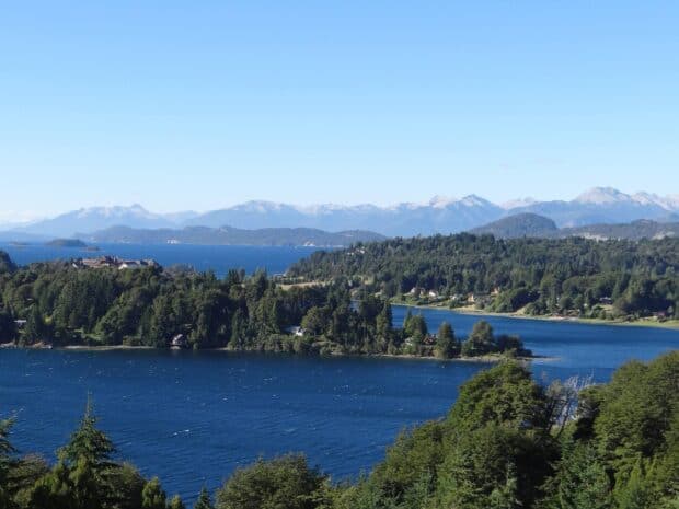 The Nahuel Huapi features clear blue water surrounded by green forest and distant mountains, HD Desktop Wallpaper