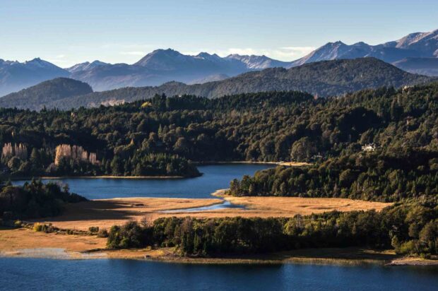 A serene view of Nahuel Huapi with forested hills and mountains under clear skies, HD Desktop Wallpaper