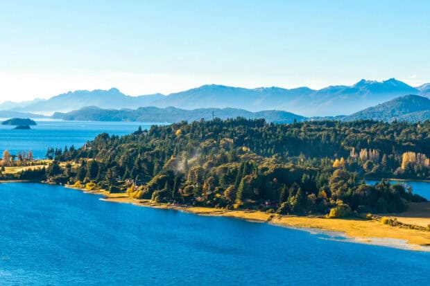 A panoramic view of Nahuel Huapi with clear blue water and lush green forests, 2K Desktop Wallpaper