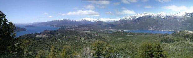 A panoramic view of Nahuel Huapi with snowy peaks and forested land under a clear sky, 2K Desktop Wallpaper