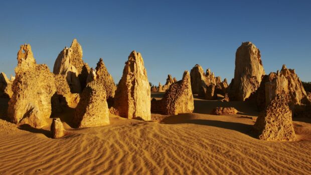 The towering limestone formations in Nambung National Park rise above the rippled sands under a clear blue sky, HD Desktop Wallpaper