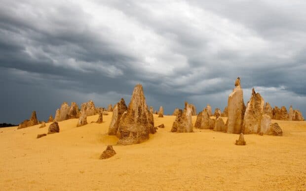 Unique rock formations are scattered across Nambung National Park under a cloudy sky, 2K Desktop Wallpaper