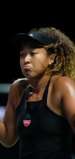 Naomi Osaka focused intensely during a tennis match under the lights, HD Phone Wallpaper