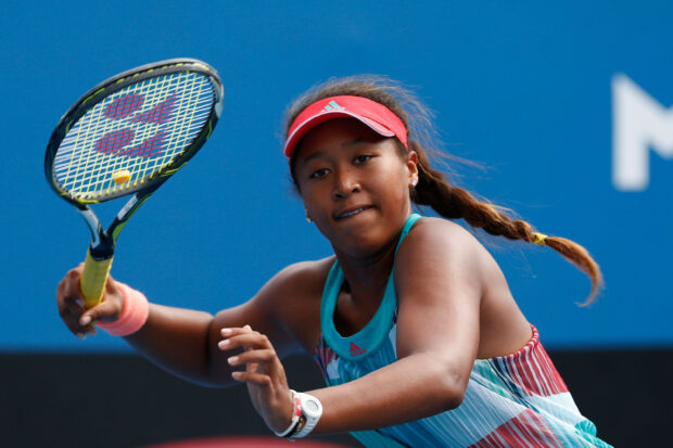 Naomi Osaka returning a tennis ball during a match with focus and determination, 2K Desktop Wallpaper