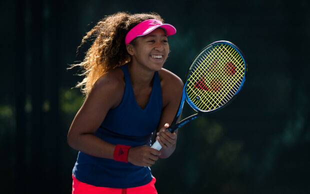 Naomi Osaka smiles while holding a tennis racket on court, 2K Desktop Wallpaper