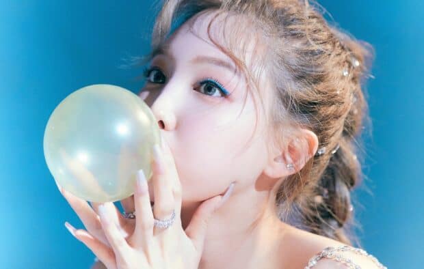 A close up of Nayeon blowing up a balloon with a bright blue background, HD Mobile Wallpaper