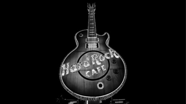 A glowing hard rock guitar sign shines brightly against a dark background, 2K Desktop Wallpaper