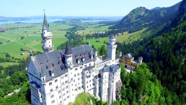Neuschwanstein Castle stands surrounded by green hills and trees, HD Desktop Wallpaper