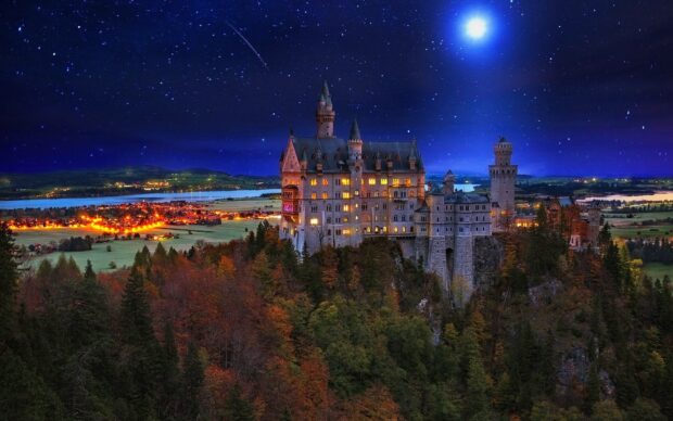Neuschwanstein Castle shines brightly under the starry night sky with surrounding autumn trees, HD Desktop Wallpaper