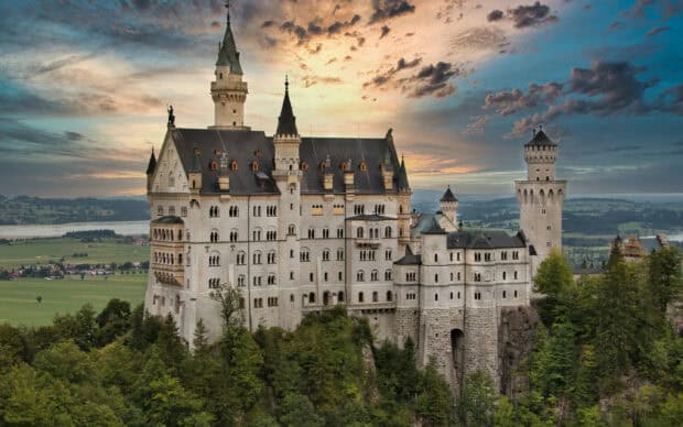 Neuschwanstein Castle stands majestically with a colorful sky in the background, 2K Desktop Wallpaper