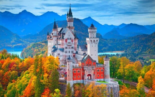 Neuschwanstein Castle stands surrounded by colorful autumn trees and distant mountains, HD Desktop Wallpaper