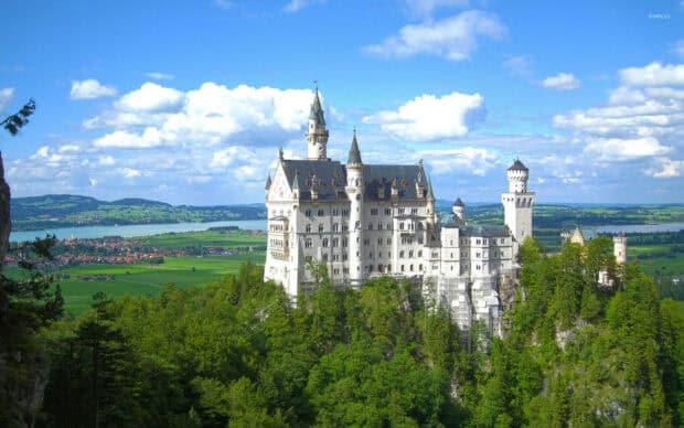 The Neuschwanstein Castle stands among green forests under a partly cloudy blue sky, HD Desktop Wallpaper