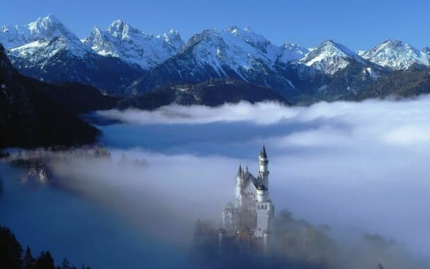 Neuschwanstein Castle stands surrounded by mist and snow covered mountains, HD Desktop Wallpaper