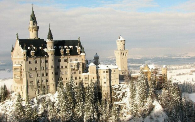 The Neuschwanstein Castle is surrounded by snow covered trees under a cloudy sky, HD Desktop Wallpaper
