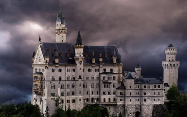 The Neuschwanstein Castle stands tall against a dramatic cloudy sky, 2K Desktop Wallpaper