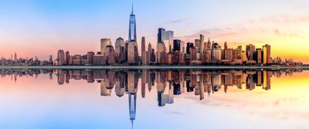 New York skyline showcases tall buildings and reflections in water at sunset, 2K Desktop Wallpaper