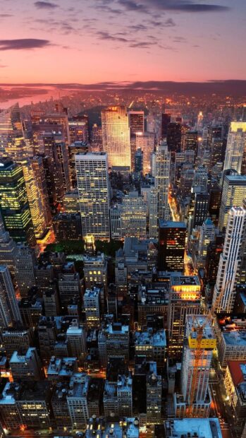 The New York skyline shows a vibrant cityscape glowing at sunset with tall buildings, HD Phone Wallpaper