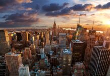 The New York skyline shows tall buildings lit by the sunset with a dramatic sky, 4K Desktop Wallpaper