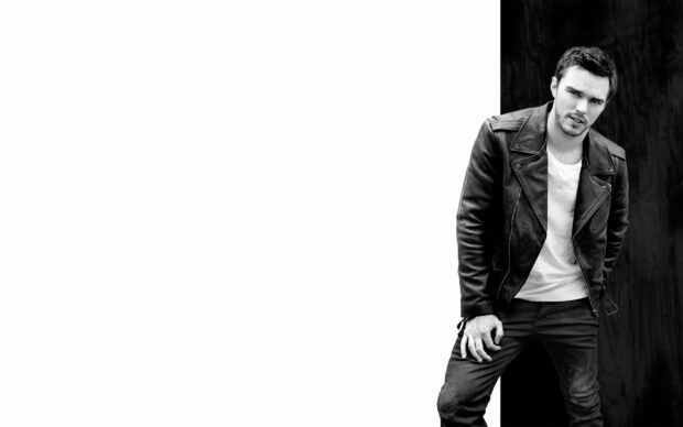 Nicholas Hoult is wearing a leather jacket and white shirt standing against a dark wall, 2K Desktop Wallpaper