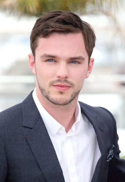 A close up portrait of Nicholas Hoult with blue eyes wearing a dark suit jacket and white shirt, 2K PC Wallpaper