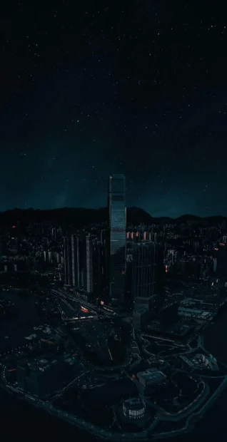 A tall skyscraper stands illuminated under a starry night sky in the cityscape for iPhone 17 Wallpapers, 2K Phone Wallpaper