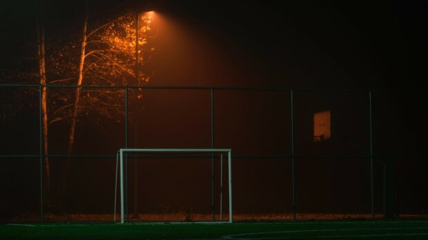 A nighttime football goal is lit by a street lamp on the field, 4K Desktop Wallpaper