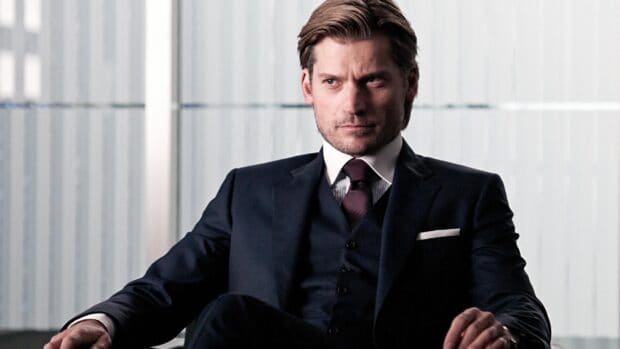 Nikolaj Coster Waldau is sitting with a serious expression wearing a dark suit and tie, 2K Desktop Wallpaper