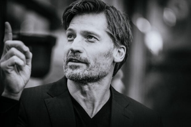 A black and white portrait of Nikolaj Coster Waldau looking upward and pointing, 2K Desktop Wallpaper