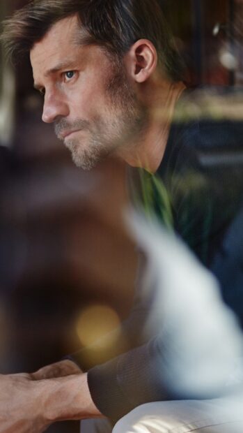 Nikolaj Coster Waldau shows a pensive expression while sitting indoors, HD Mobile Wallpaper