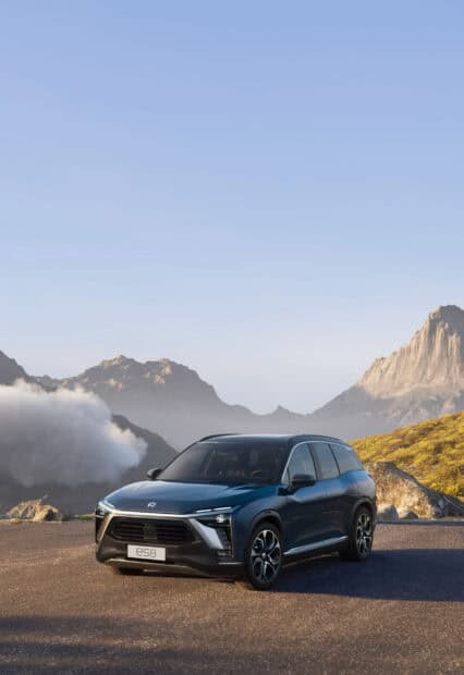 A Nio auto drives on a road with mountains in the background, 2K Phone Wallpaper