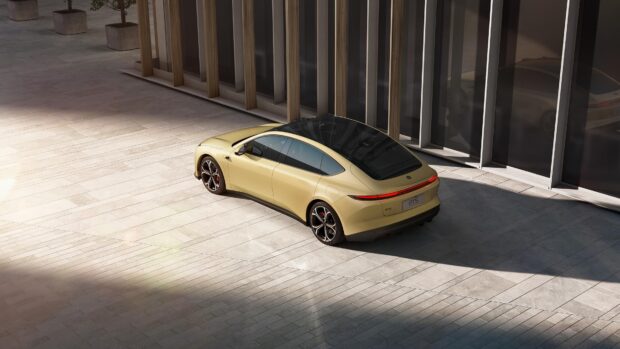 A beige Nio Auto car is parked beside modern building walls in soft sunlight, 4K Desktop Wallpaper